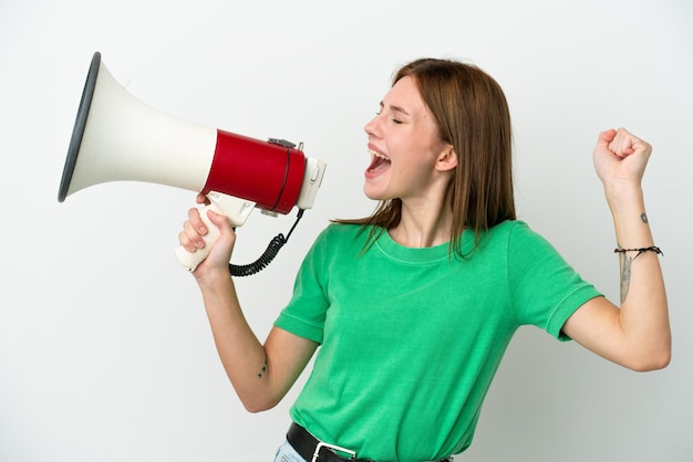 Young English woman isolated on white background shouting through a megaphone to announce something in lateral position