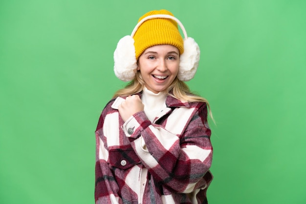 Young English woman wearing winter muffs over isolated background celebrating a victory