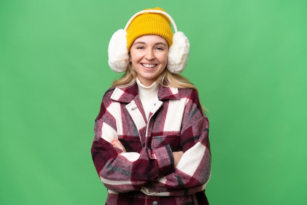 Young English woman wearing winter muffs over isolated background keeping the arms crossed in frontal position