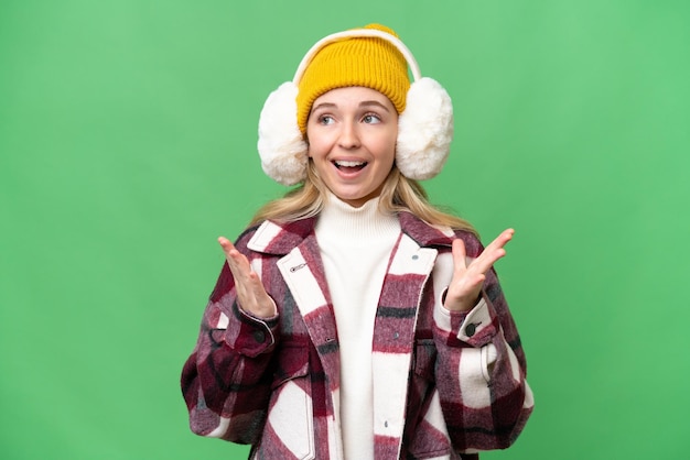 Young English woman wearing winter muffs over isolated background with surprise facial expression