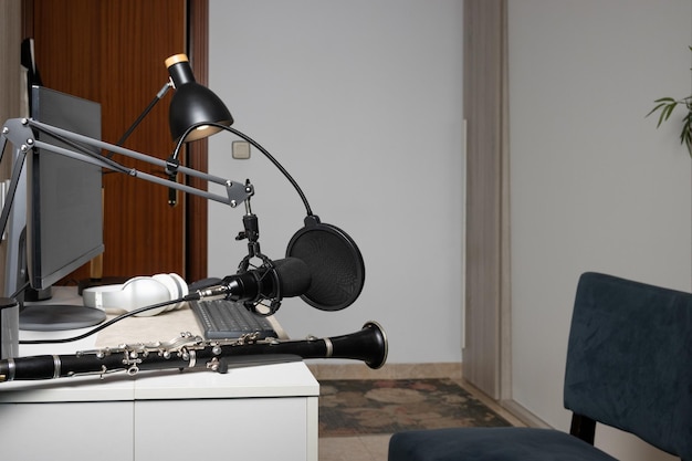 Young entrepreneur playing the clarinet at home and recording music to stream it online with his computer indoor