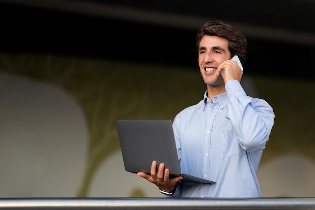 Young entrepreneur with laptop in his hand have phone conversation