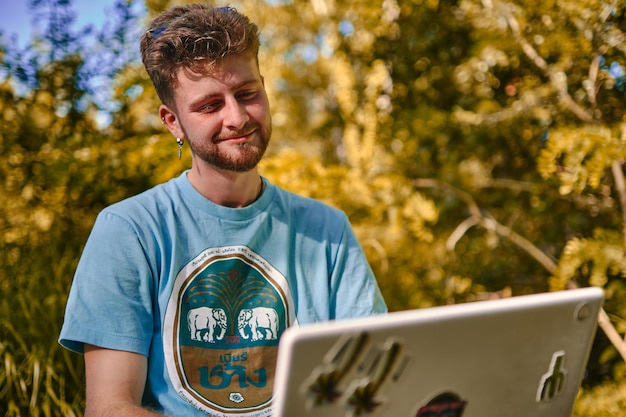 Young entrepreneur working outdoors on his project on his laptop with a serious face Blond studying with a laptop in a park