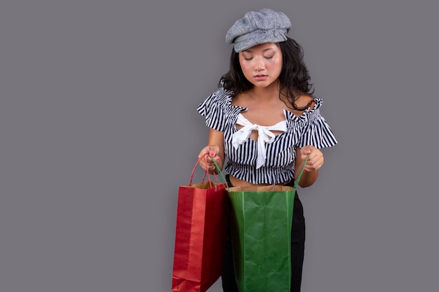 Young ethnic asian girl with shopping bags isolated on gray background