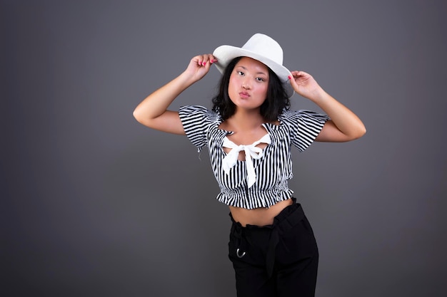 Young ethnic asian woman posing with white hat isolated from background