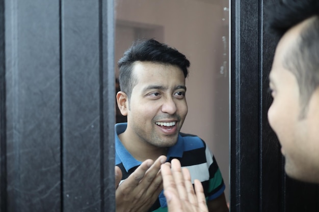 Young ethnic male looking in the mirror and talking to himself