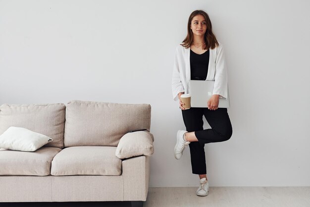 Young european girl in formal clothes is indoors with laptop