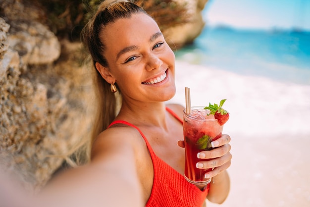 Young European woman in bikini on the beach in summer Girl using her smartphone Taking photos selfie