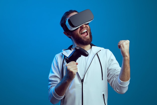 Young excited bearded man standing with the vr equipment and playing