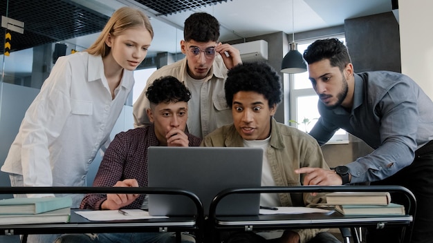 Young excited happy businesspeople team in office looking at laptop screen reading good news group