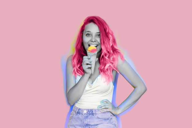 Young excited smiling woman with pink wavy hair eats fruit ice-cream sorbet in a waffle cone