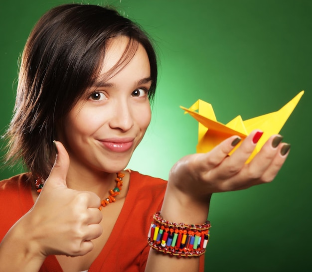 Young expression woman with paper bird over green background