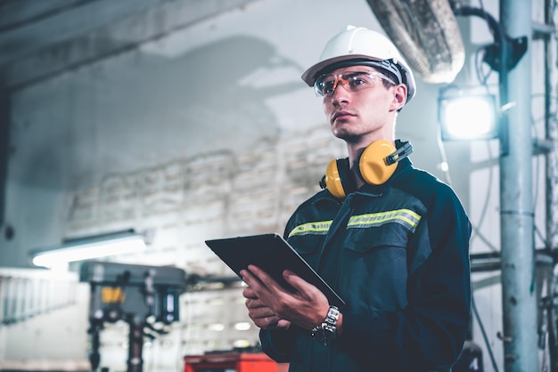 Young factory worker using adept tablet computer in a workshop building