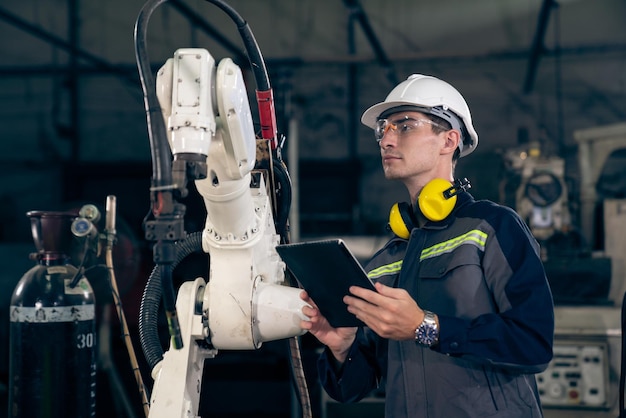 Young factory worker working with adept robotic arm