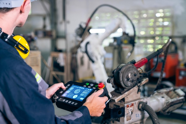 Young factory worker working with adept robotic arm