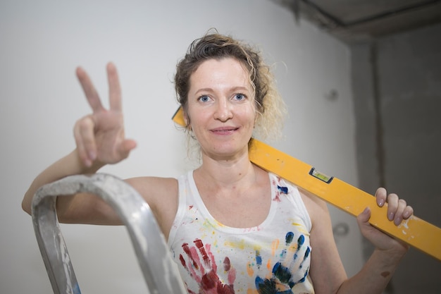 Photo young fairhaired curly woman makes repairs in the dwelling with construction tools