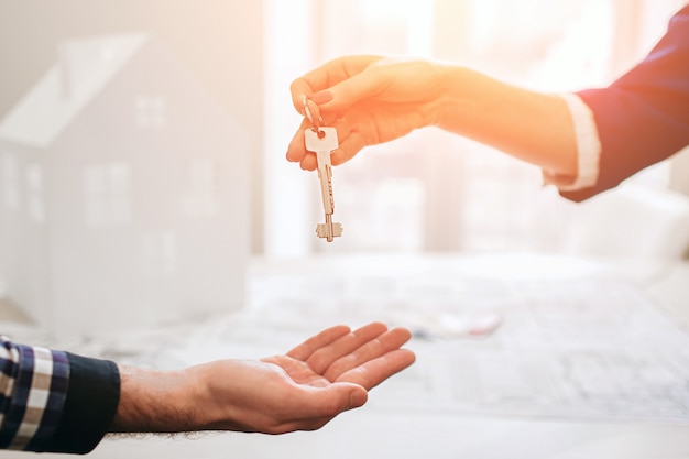 Young family couple purchase rent property real estate . Agent giving consultation to man and woman. Signing contract for buying house or flat Giving keys to couple of customers. Close up.