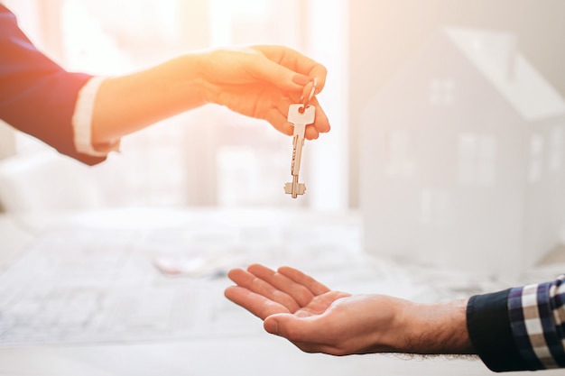 Young family couple purchase rent property real estate . Agent giving consultation to man and woman. Signing contract for buying house or flat Giving keys to couple of customers. Close up.