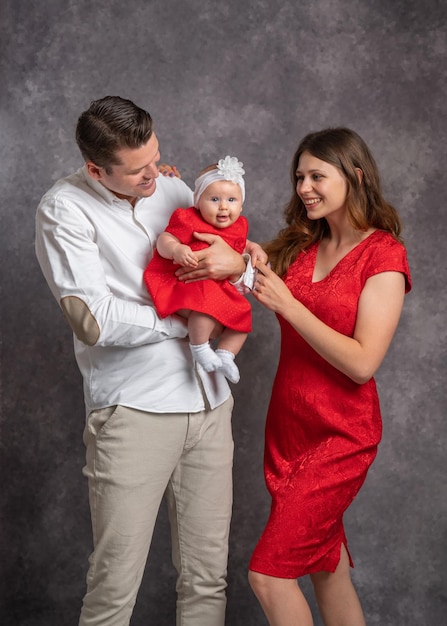 Young family dad mom holding baby daughter in her arms Studio shooting