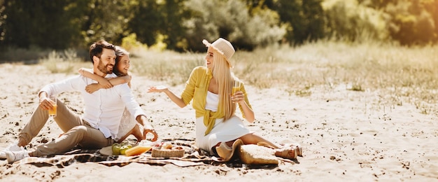 Photo young family enjoying picnic sitting on blanket in nature spending time together