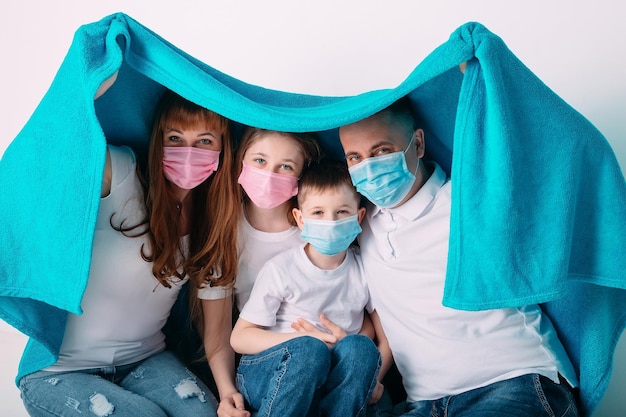 Young family in medical masks during home quarantine.