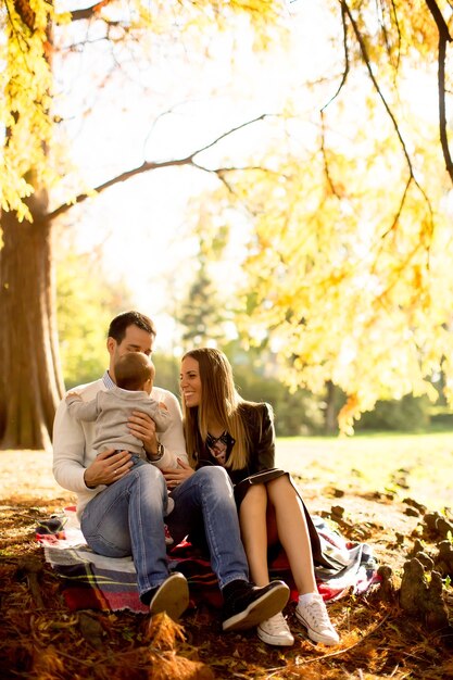 Young family sitting on the ground in autumn park