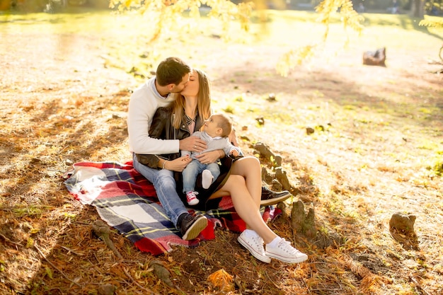 Young family sitting on the ground in autumn park