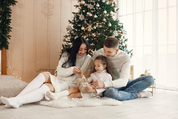 Young family sitting near Christmas tree and celebrating together