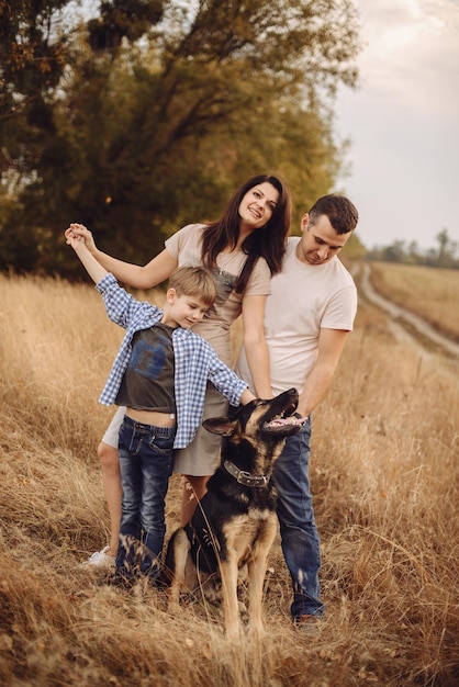 Young family and their dog spend time on nature in the autumn afternoon