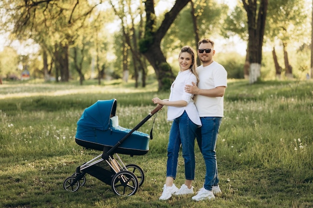 A young family walk in the park in with a toddler in a stroller Happy parents