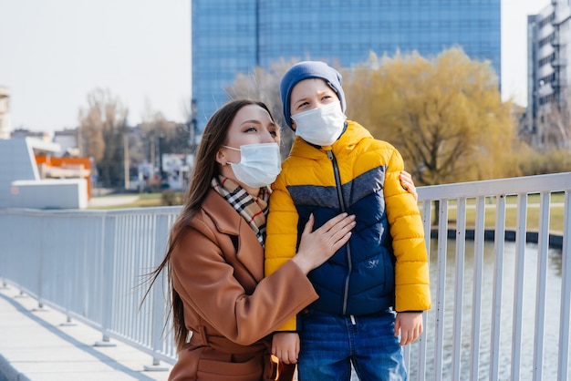 A young family walks and breathes fresh air on a Sunny day during a quarantine and pandemic. Masks on people's faces.