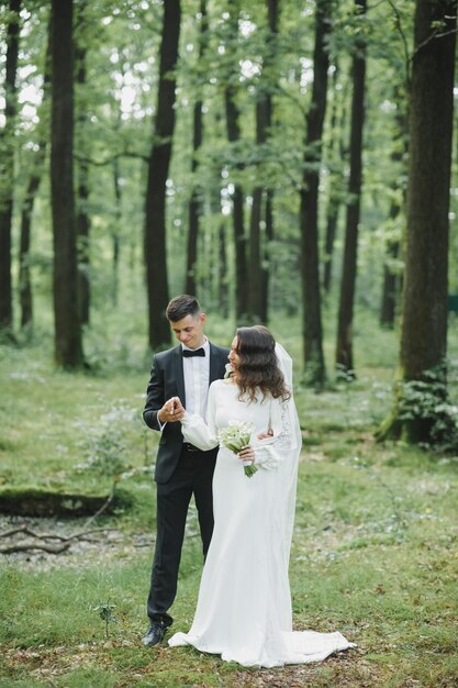 young family, the wedding, the newlyweds. Bride and groom walk around the trees