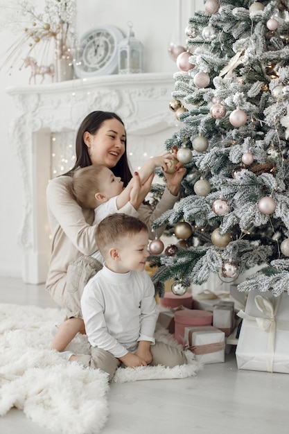 Young family in white clothes decorating the Christmas tree at home