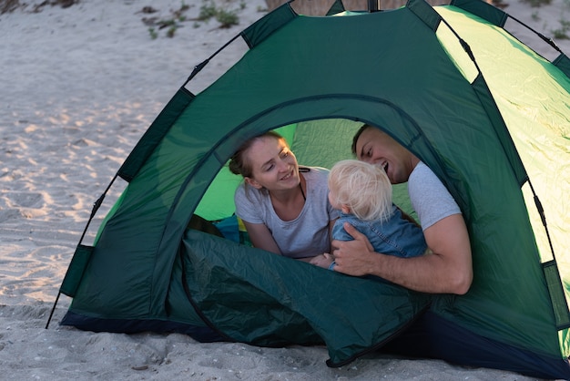 Young family with child in green tourist tent at the campsite. Vacation with children.