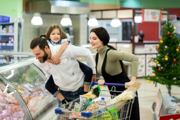 Young family with a little girl shopping in a large supermarket. Concept of a new year.