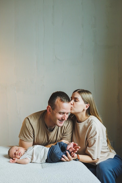 A young family with a newborn baby Happy mother and father kissing their child Parents and a smiling child in their arms