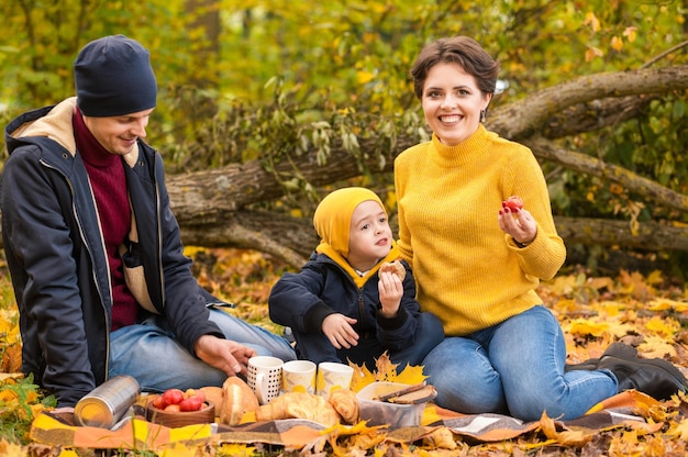 A young family with small boy having picnic in autumn nature