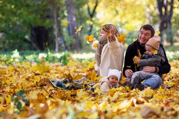 A young family with small children in the autumn park rejoice in the beautiful season on a sunny day