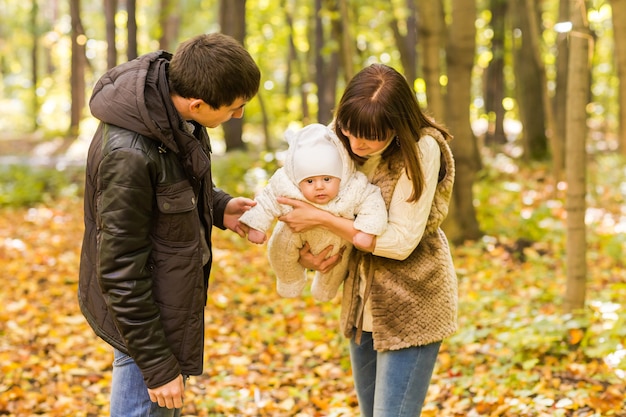 Young family with their newborn baby spending time outdoor in the autumn park.