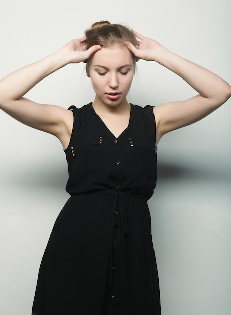 Young fashion blond woman in black dress posing in studio