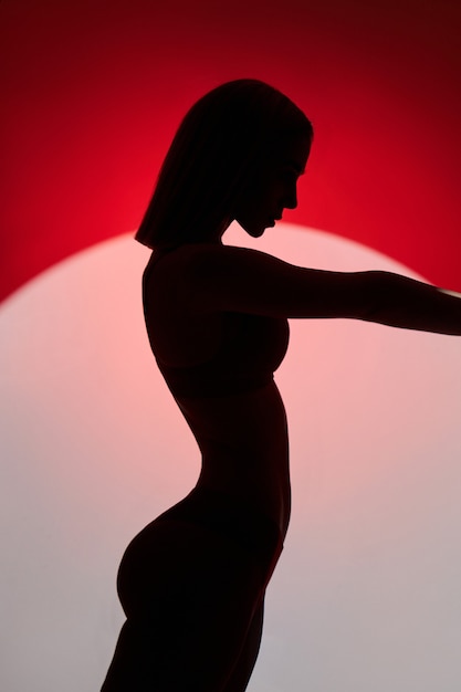 Young fashion woman in red lingerie underwear swimsuit light and shadow, sensitive woman posing in a circle of light