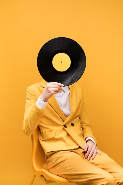 Young fashionable man holding vinyl in front of face