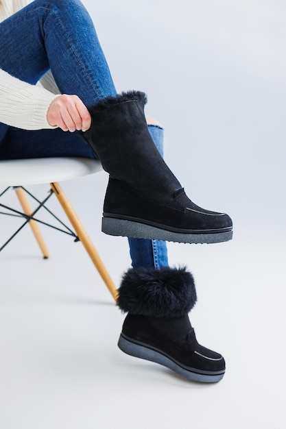 A young fashionable woman in stylish jeans and trendy leather shoes is standing on a white tile Fashionable collection of women's autumn shoes Closeup of female legs in shoes