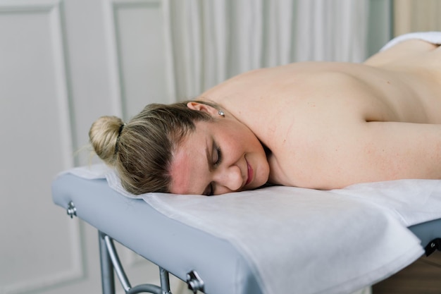 Young fat woman getting massage treatment in day spa cabinet