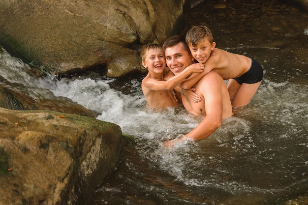 A young father and his sons bathe in a mountain river