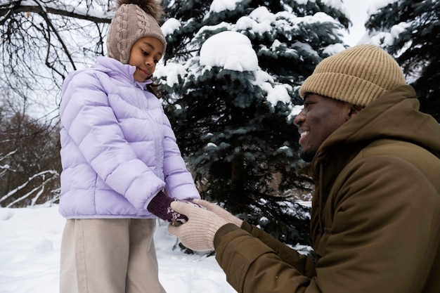 Young father holding his daughter's hands to warm them up on a winter day