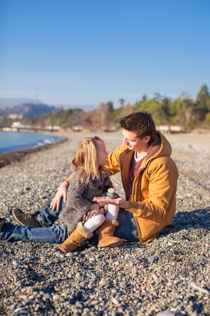 Young father and little girl at the beach on a sunny winter day