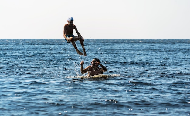 A young father throws his son off his shoulders into the water on Lake Ladoga