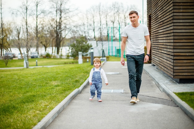 Young father with his daughter walking in the city park