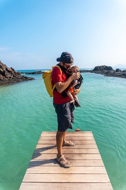 A young father with his son on the wooden walkway by the sea on Isla de Lobos, off the north coast of the island of Fuerteventura, Canary Islands. Spain